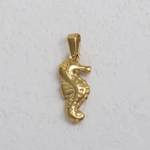 Detail view of 24K gold plated seahorse pendant with textured metallic surface for jewelry