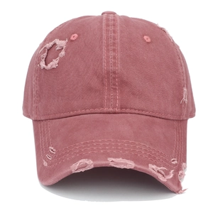 Close-up of pink vintage distressed baseball cap with ripped details and worn edges