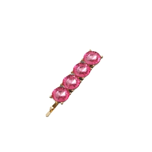 Detailed close-up of a golden metal hair clip with four pink round rhinestones