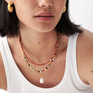 Detail of layered colorful beaded necklaces with a baroque pearl pendant and gold hoops