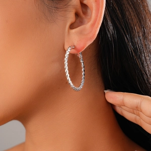 Macro side view of silver twisted rope hoop earring worn by a model for size and fit