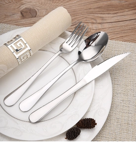 Stainless steel cutlery set on white plate with greek pattern napkin ring decor
