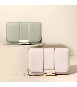 Detail of green and pink PU leather wallets with classic metal hardware on a display