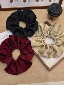 Three-piece jacquard satin scrunchies in black, burgundy, and champagne gold floral fabric