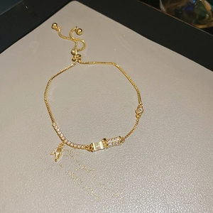 Macro detail of adjustable gold plated bracelet with cat eye stone and leaf charm