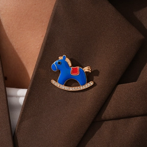 Close-up of blue enamel rocking horse brooch with rhinestones on a brown blazer lapel