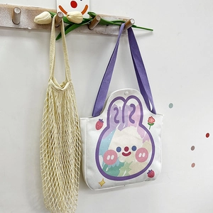 Detail of white canvas tote bag featuring purple rabbit cartoon print and woven shoulder strap