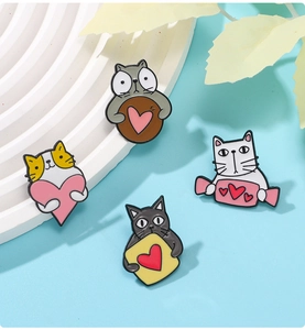 Detail of four cute enamel cat brooches with heart motifs on a blue background