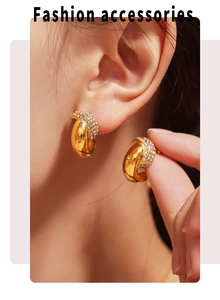 Detailed close-up of crescent hoop earrings with white crystals in 18k gold plating