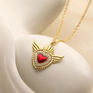Macro di una collana con ciondolo a cuore alato placcato oro con zircone rosso e corona