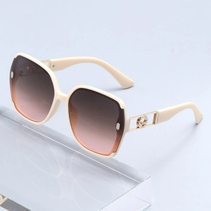 Detail view of beige oversized sunglasses with gradient lenses and gold metal temple accents
