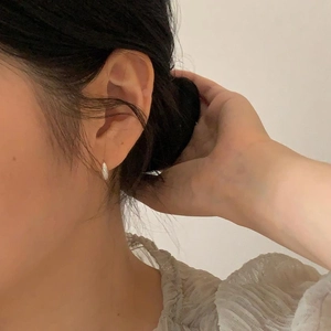Close-up of minimalist silver zircon earrings worn by a model for a chic look