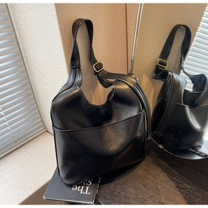 Details einer schwarzen Leder-Shopper-Tasche mit breitem Gurt und goldenen Beschlägen