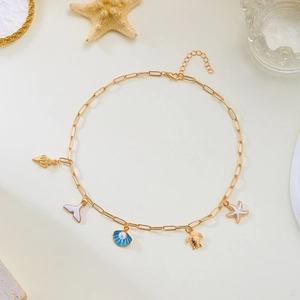 Detail of beach themed gold necklace with starfish, shell, and turtle charms on beige background