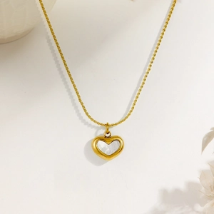 Macro shot of gold heart necklace with white shell inlay and delicate twist chain