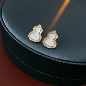 Macro shot of gold gourd earrings with white inlay and sparkling pavé stones