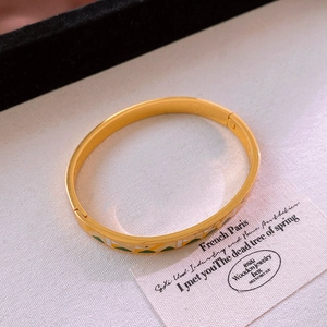 Détail d'un bracelet vintage en acier titane doré avec incrustations d'émail géométriques