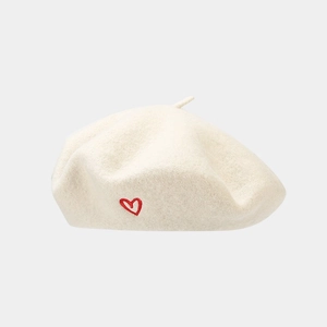 Detailed view of cream-colored wool beret featuring a delicate red heart embroidery