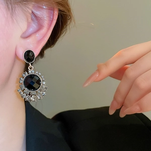 Close-up of vintage black gemstone earrings with diamond halo worn on a model ear