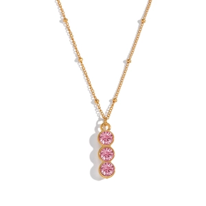 Close-up of golden beaded Y-necklace featuring three vertical pink cubic zirconia stones