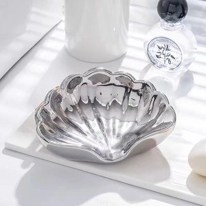 Dettaglio portasapone in ceramica argentata a forma di conchiglia con finitura metallica