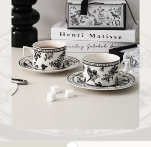 Detail of vintage ceramic coffee cup set with black floral patterns and gift packaging