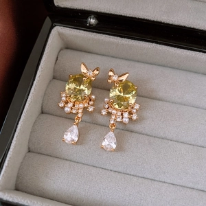 Detail of vintage 18k gold butterfly earrings with yellow gemstone and pearls