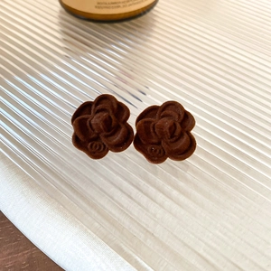 Close-up of brown flocked camellia earrings with velvet texture and metal detail
