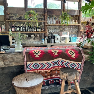 Macro shot of bohemian geometric knit blanket with tassels on a rustic wooden counter
