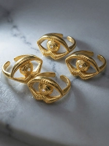 Macro shot of gold-plated evil eye rings with white zircon on marble background