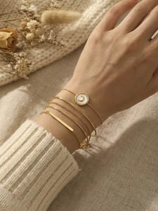 Close-up of five-piece gold bracelet set with moon pendant and natural white shell detail
