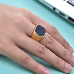 Close-up of a minimalist 18K gold ring with a black square inlay on a model's hand