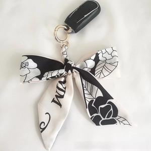 Close-up of camellia silk bow keychain with gold ring attached to a car key