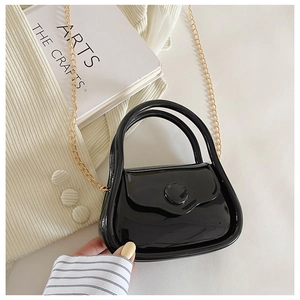 Close-up of black jelly mini bag with glossy patent finish and fine gold metal chain
