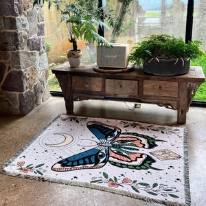 Detail of woven camping blanket featuring butterfly patterns and fringe edge