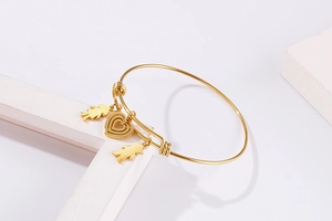 Detail of adjustable gold heart bracelet with romantic charm pendants on geometric display