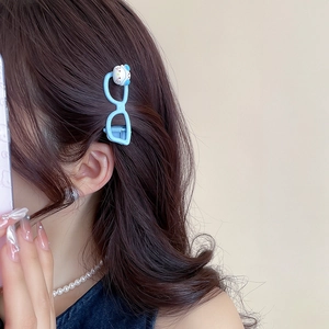 Detail shot of a light blue kitty glasses hair clip styled on wavy brunette hair