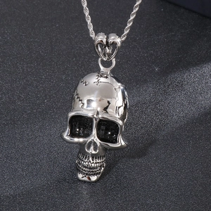 Detailed view of silver skull pendant with vintage patterns on a black textured background
