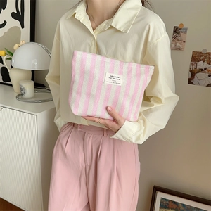Close-up of pink and white striped fabric toiletry bag with white logo label