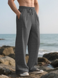 Close-up of men's dark grey wide leg trousers with textured stripes and drawstring waist