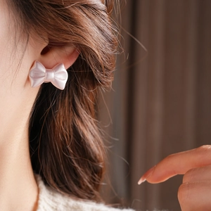 Close-up of pink pearlescent bow stud earring worn on model for a sweet aesthetic