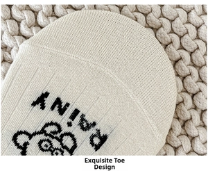 Detail of light beige cotton socks showing knitted ribbing with bear and RAINY text