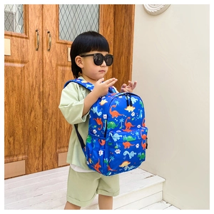 Blue waterproof kids backpack with cartoon dinosaur prints worn by a child model