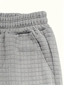 Close-up of gray quilted sports shorts with elastic waistband and side pocket detail