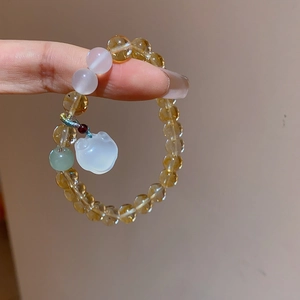Close-up of beaded bracelet with chalcedony, yellow crystals, and a white cat charm