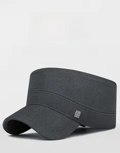 Detail of dark grey flat top cap showing cotton twill texture and small metal logo badge