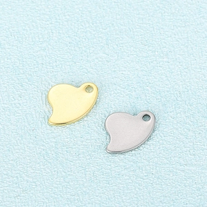 Golden and silver irregular heart-shaped stainless steel charms with ring loops on blue cloth