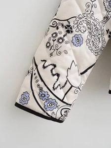 Detail of quilted white jacket featuring black paisley patterns and contrasting black piping