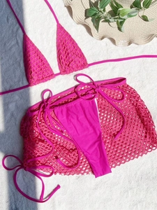 Detail of hot pink three-piece bikini set with mesh skirt on white textured background