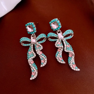 Detail of vintage bow earrings featuring pink gemstones and turquoise beads on silver metal